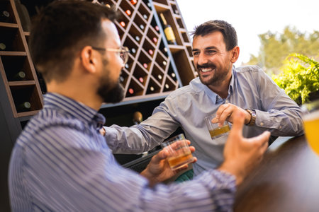 Two male friends hanging out at the restaurant and drinking short drink.の写真素材