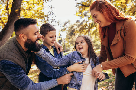 Parents tickle their children. Sunny autumn day in the colorful parkの写真素材