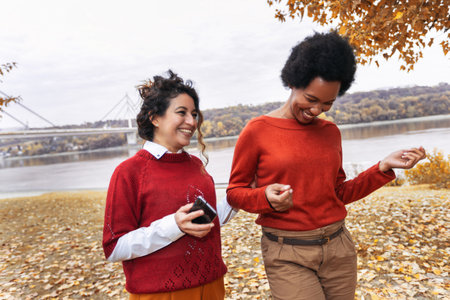 Two smiling young women friends jogging outside in the forest next to the lake in red sweatshirtsの写真素材