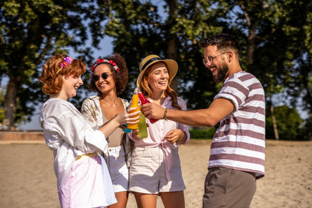 Group of friends hanging out at the beach on a sunny day. They toast and drink alcohol.の写真素材