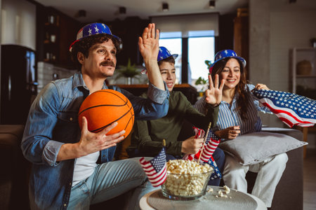 Latino family is watching basketball match with American flag.の写真素材
