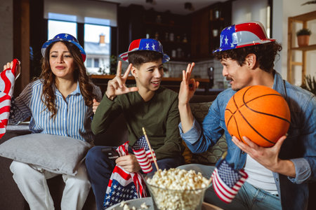 Latino family is watching basketball match with American flag.の写真素材