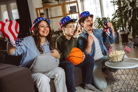 Latino family is watching basketball match with American flag.の写真素材