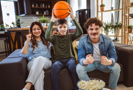 Latino family is watching basketball match and eating popcorn.They are cheering for their team.の写真素材