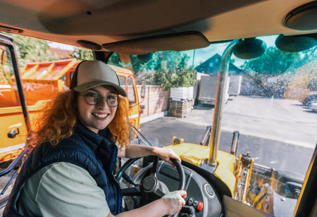 Young ginger woman drives an excavator.の写真素材