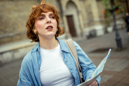 Female ginger tourist using a map while exploring the new city.