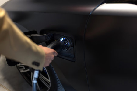 Young businessman at the charging station holding a plug to charge his electric car. Eco electric car conceptの写真素材