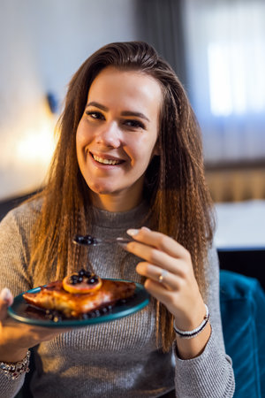 Pretty girl eating delicious pie in her apartment.の写真素材