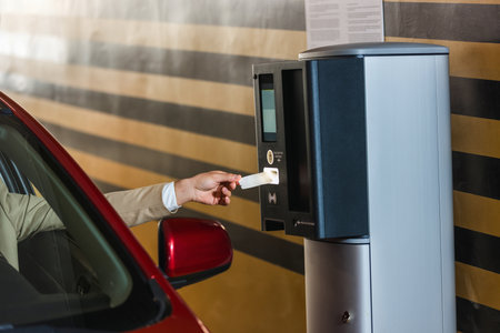 Young man entering a parking lot. Taking a ticket for paying the garage.の写真素材