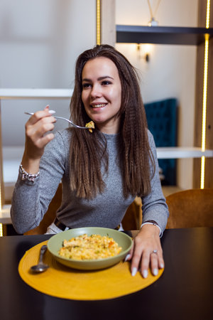 Woman eating mac and cheese in her apartmen.の写真素材