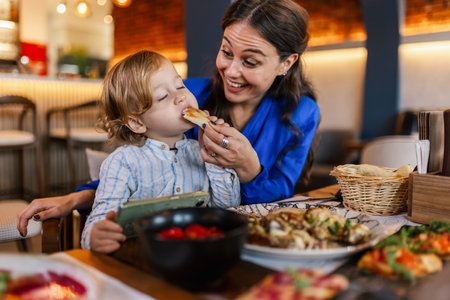 Mother feeding her son with food in restaurant.の写真素材