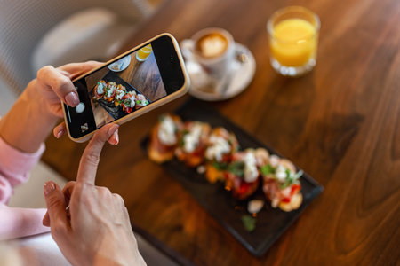 Woman influencer taking pictures of food in a restaurant. Social media. Food and drink concept.の写真素材