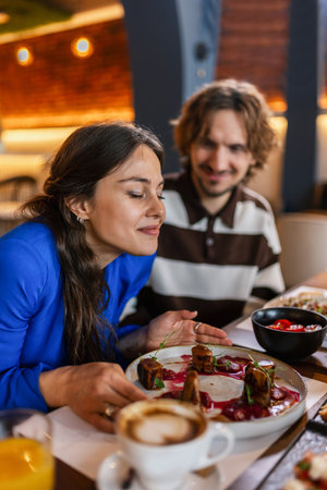 Couple in a restaurant eating delicious food. Girlfriend smelling the food. Food and drink concept.の写真素材