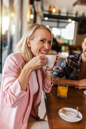 Young cheerful woman drinking hot drink in a restaurant.の写真素材