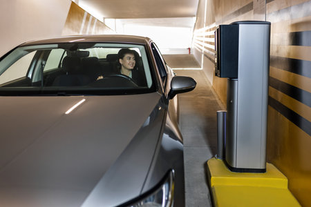 Young woman entering a parking lot. Taking a ticket for paying the garage.の写真素材