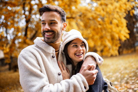 Young happy couple hugging and walking in the park. Colorful park on sunny autumn day.の写真素材