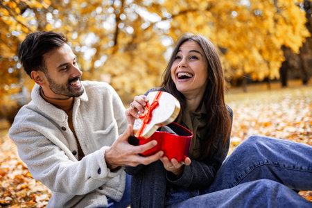 Boyfriend surprises his girlfriend on Valentines day with a gift on a picnic.の写真素材