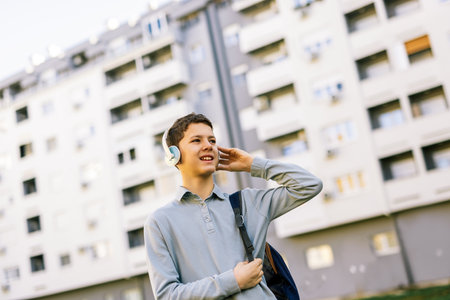 A young boy walking down a city street, wearing headphones over his earsの写真素材
