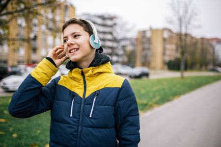 A young boy walking down a city street, wearing headphones and dressed in warm winter clothingの写真素材