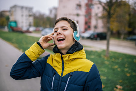 A young boy walking down a city street, wearing headphones and dressed in warm winter clothingの写真素材