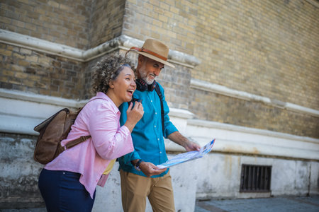 Portrait of happy senior couple tourists outdoors in historic town using map.の写真素材