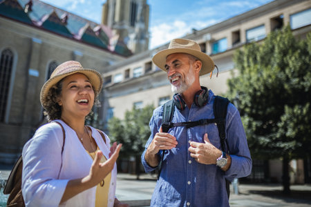 Senior couple of tourists stands happily in front of a stunning city fountain, surrounded by historic architectureの写真素材