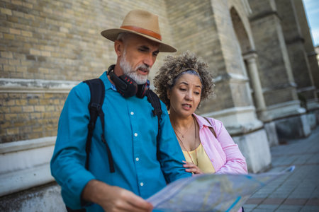 Portrait of happy senior couple tourists outdoors in historic town using map.の写真素材