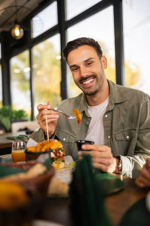 Man enjoying his lunch at a restaurant, sitting at a table with a delicious meal in front of him.の写真素材