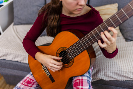 Young woman strumming her guitar in the comfort of her room.の写真素材