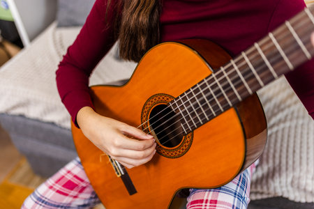 Young woman strumming her guitar in the comfort of her room.の写真素材