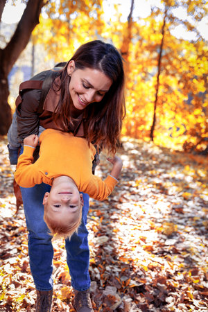 Mother hugging her child during walk in the park and having fun.