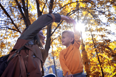 Adorable little boy with his mother in autumn park having fun.