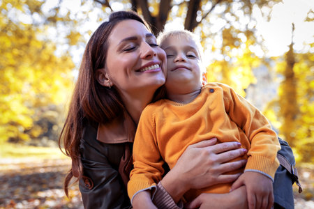 Adorable little boy with his mother in autumn park having fun.