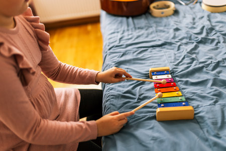 Closeup of little girls hands playing metallophone.