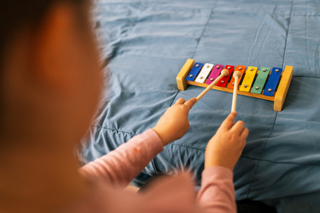 Closeup of little girls hands playing metallophone.