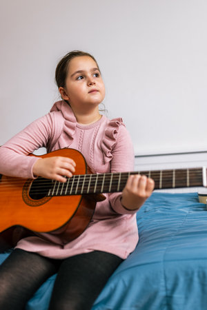 Little girl playing guitar in her room.