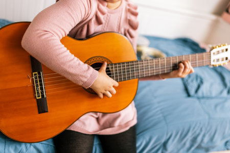 Little girl playing guitar in her room.の写真素材