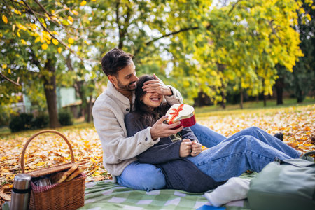 Boyfriend surprises his girlfriend on Valentines day with a gift on a picnic.の写真素材