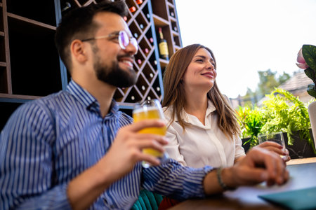 Group of friends hanging out in restaurant and drinking beer. Having fun, talking and making memories.の写真素材