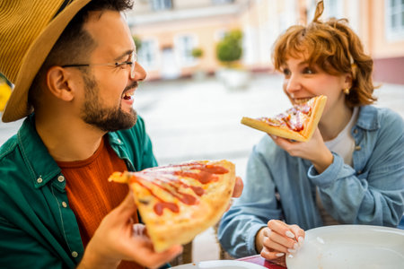 Couple in restaurant eats delicious looking pizza with ketchup.の写真素材