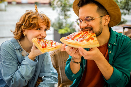 Couple in restaurant eats delicious looking pizza with ketchup.の写真素材