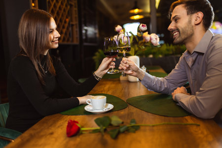 Man and woman toasting with white and red wine in the restaurant while they are on a romantic dinner date.の写真素材