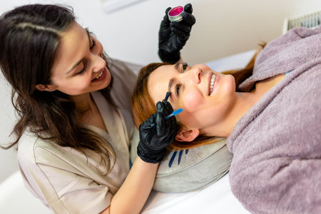 Beauty professional applying eyebrow tint to a woman's brows using a fine brush.の写真素材