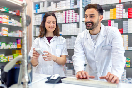 Two young pharmacist using computer at counter.の写真素材