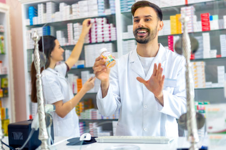 A young pharmacist is offering medicine to a customer in a pharmacy, showcasing the professional interaction between pharmacy staff and clients.の写真素材