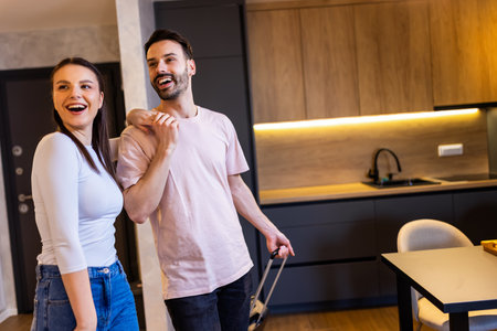 Young couple comes into the apartment for their vacation. They carry the baggage with them.の写真素材