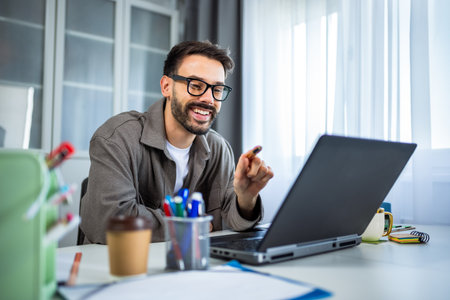 A young man working from home on his laptop in a modern, cozy home environment.の写真素材
