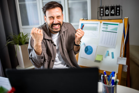 A man smiling and feeling happy while working on his laptop at home.の写真素材