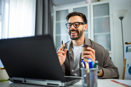 A young man working from home on his laptop in a modern, cozy home environment.の写真素材