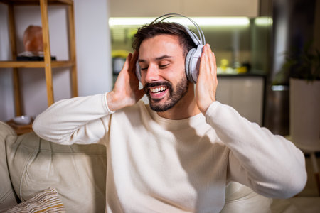 A young man relaxing at home while listening to music through headphones.の写真素材